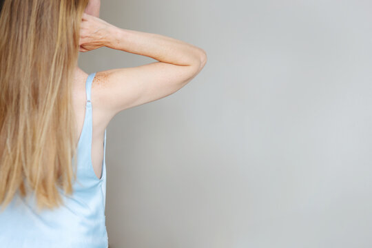 Back view of a woman with long blonde hair in a blue satin top, showing natural skin and freckles with copy space.