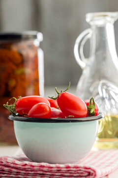 Fresh Cherry Tomatoes in a Bowl with Olive Oil and Preserved Jar on Kitchen Counter