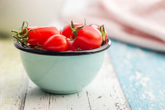 Fresh Red Cherry Tomatoes in a Blue Enamel Bowl on a Rustic Wooden Table