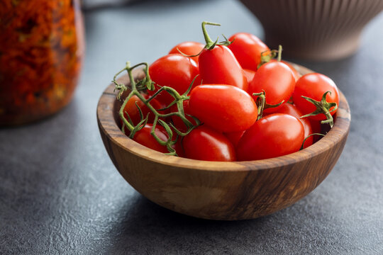 Fresh Cherry Tomatoes in Wooden Bowl on Kitchen Countertop, Close-Up Bright Red Produce