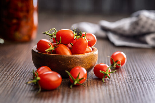 Fresh Cherry Tomatoes in Wooden Bowl on Rustic Tabletop Close-Up with Natural Kitchen Background