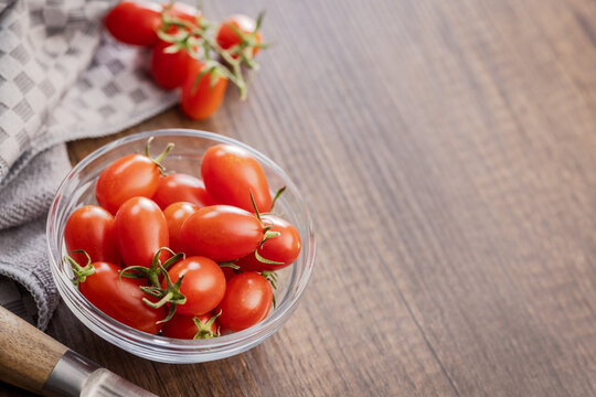 Fresh Cherry Tomatoes in Glass Bowl on Wooden Table With Kitchen Towel