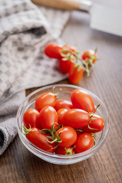 Fresh Cherry Tomatoes in Glass Bowl on Wooden Table With Kitchen Towel