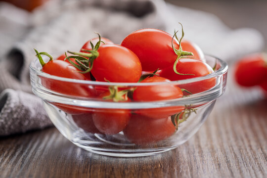 Fresh Cherry Tomatoes in Glass Bowl on Wooden Table With Kitchen Towel