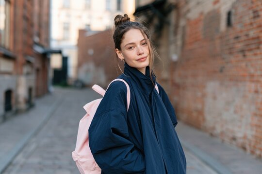 Young woman street portrait with pink backpack and navy jacket for lifestyle poster background and casual urban design