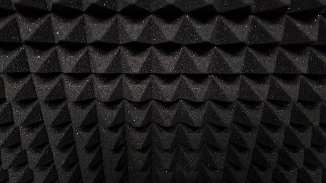 Black triangular foam pads form a repeating pattern. Uniform, rigid, dark texture dominates the frame. Geometric shape repeats across entire visible surface. Pattern appears static