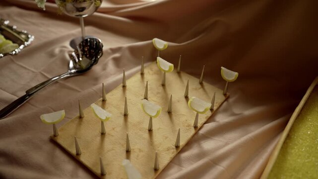 Low-angle tabletop display of wooden spike board topped with translucent lime sugar candies under warm satin drape lighting, with candy, lime, sugar, spike detail