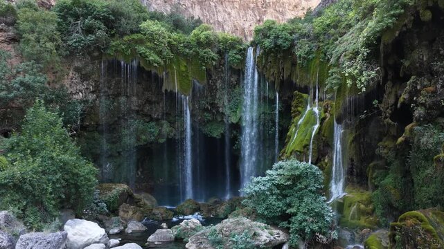 Static wide shot of a beautiful lush waterfall cascading over mossy rocks.