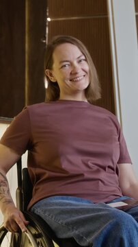 Portrait of Caucasian young adult woman with disability sitting in wheelchair, turning to camera and smiling. Ideal for diversity, inclusion, and healthcare marketing campaigns, vertical