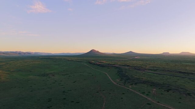 Top down aerial shot pulling back over rugged volcanic rock and dark craggy basalt textures in twilight, highlighting raw geological patterns and barren terrain.