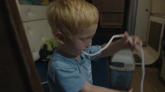 Boy plays with sailing rope inside the sailing boat.