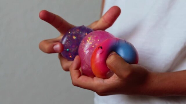 Child's hands holding colorful collectible squishy dumplings, showcasing a vibrant assortment of textures and colors in a well-lit indoor setting