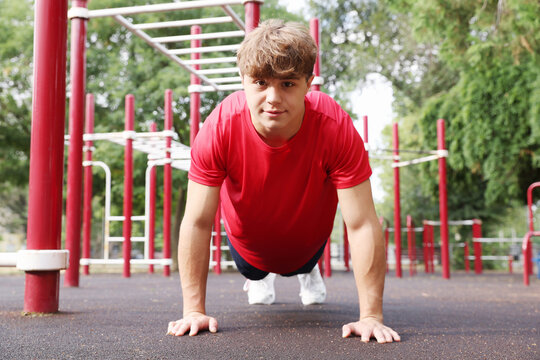 Teenage boy doing push ups at outdoor sports ground