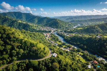 Obraz premium Aerial view of rich green mountains in Puerto Rico. Small town sits near winding river in tropical valley. Winding road leads through dense jungle, rural landscape. Scenic landscape shows mountain
