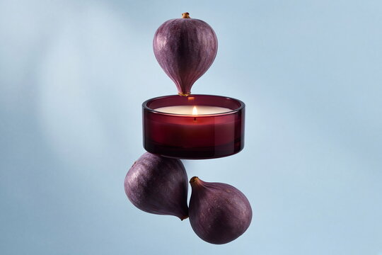 Elegant burgundy candle with fresh purple figs on a soft blue background, creative luxury still life with a glowing flame and refined color contrast.