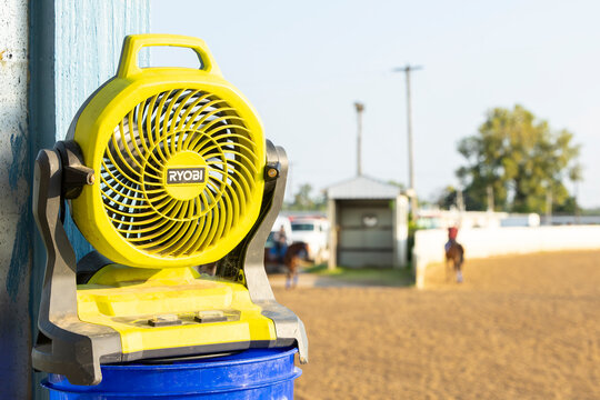 Ryobi portable fan on a bucket at a horse racetrack.
