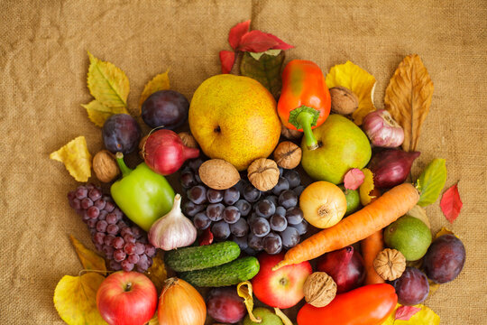 Abundant autumn harvest of organic fruits, vegetables and nuts on rustic burlap