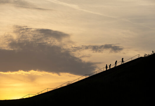 Four people climbing the stairs up Monks Mound at sunset.