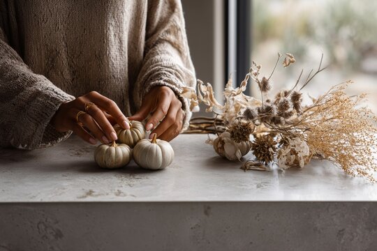 Cozy Fall Decor: Hands Arranging White Pumpkins & Dried Flowers