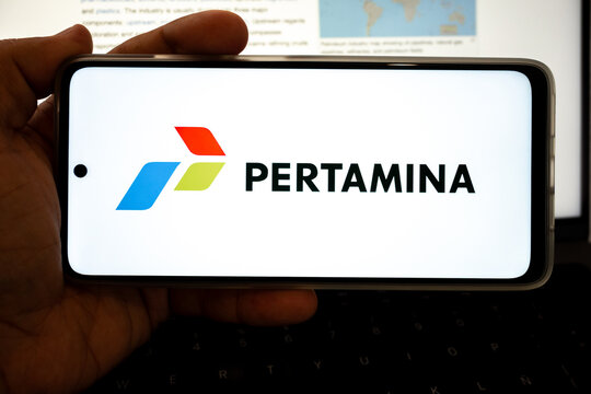 Hand holding device displaying pertamina oil and gas logo