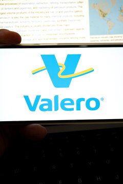 Hand holding device displaying valero logo and petroleum information
