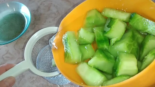 Straining nopal cactus water into a glass through a sieve 