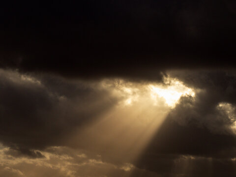 Dramatic sky with sunbeams piercing dark clouds, conveying hope or resilience