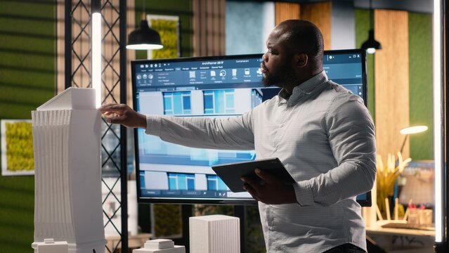 African American male developer studies zoning regulations for site preparation while working toward urban development of a residential area with a master plan for smart city infrastructure growth.