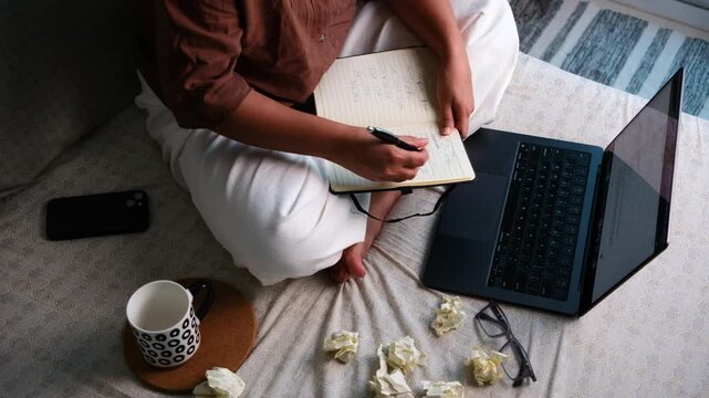 Woman brainstorming creative ideas with torn paper balls and notebook at home, ideation, creative block, problem solving and productivity concept