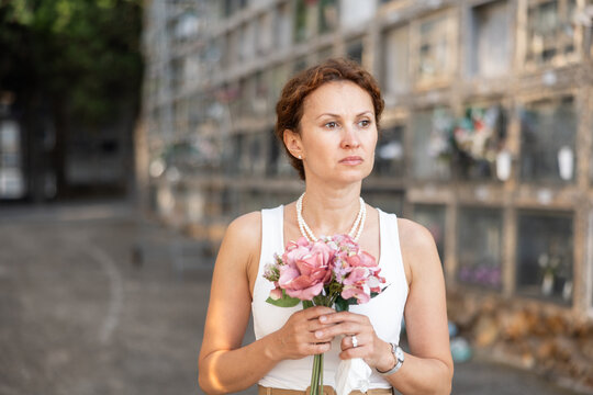Woman with bouquet of flowers came to cemetery to honor memory of deceased loved one