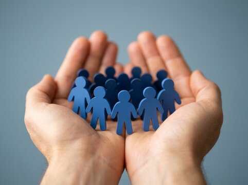 Hands holding blue human figures, symbolizing teamwork, cooperation, and community spirit in a positive light.