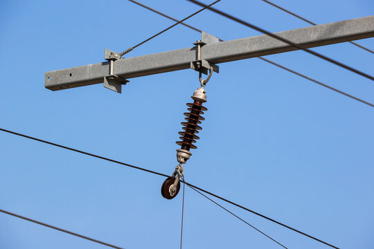 Overhead line insulator and tension pulley against blue sky