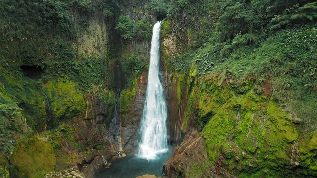 Toro waterfall flows down rocky gorge amid rich tropical greenery in Costa Rica