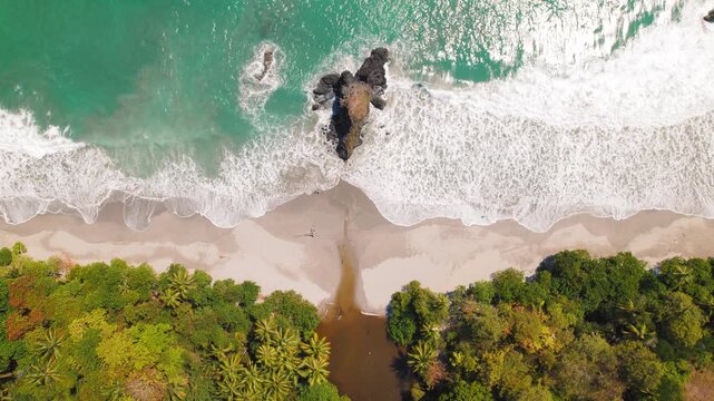Espadilla beach in Costa Rica with turquoise sea waves meeting lush green jungle