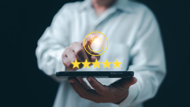 Customer satisfaction concept. Hand holding smartphone and pointing at smile icon with five star rating. Positive feedback, excellent service, user experience, quality and customer loyalty.
