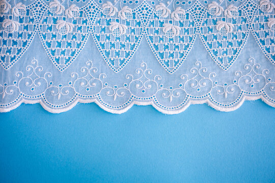 Lace pattern, detail of a tablecloth isolated on a blue background. Artistic border. Handicraft, vintage. Hobby concept. Top view.