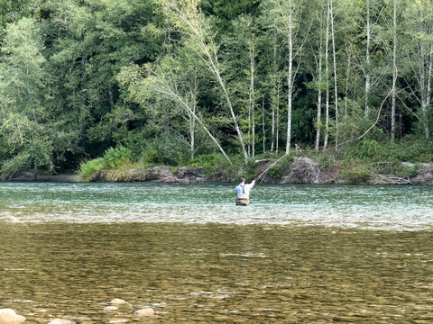 Mature retired man fly fishing the Skagit river in Washington state Cascades during summer