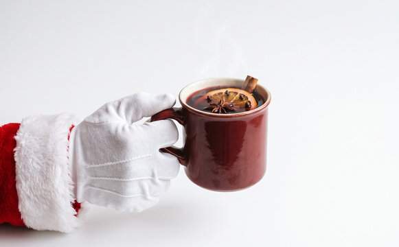 Santa Claus holding a warm mug of mulled wine with Christmas spices for holiday beverage concepts