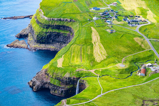 High angle aerial view of Mulafossur waterfall plunging into the ocean near Gasadalur village, Faroe Islands, Denmark