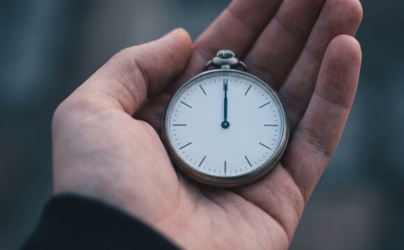 Adult man holding a vintage pocket watch in his hand representing time and deadline management concept