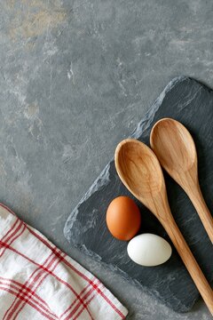 Brown and white eggs with wooden spoons on a slate board, rustic kitchen flat lay with copy space