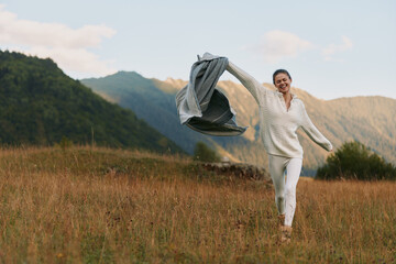 Fototapeta premium Joyful woman running in an open field with a flowing scarf, capturing carefree outdoor lifestyle and nature energy, wind lifting fabric in warm sun and vibrant sunlit mood.