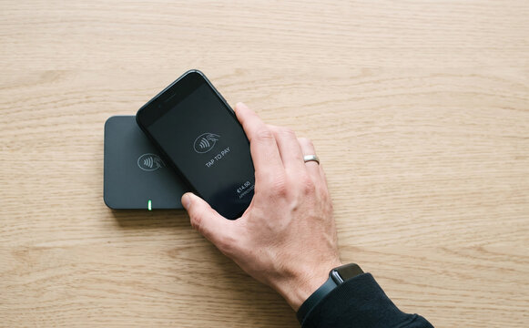Contactless payment using a smartphone and card reader on a wooden table surface for modern digital transactions