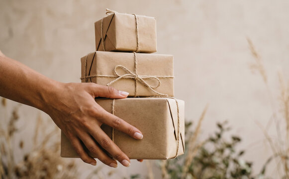 Woman holding a stack of eco friendly wrapped parcels tied with string for holiday gifting