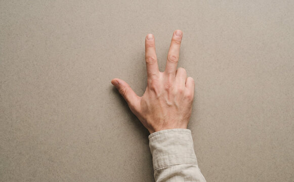 Adult man hand showing three fingers gesture against grey background concept of counting number