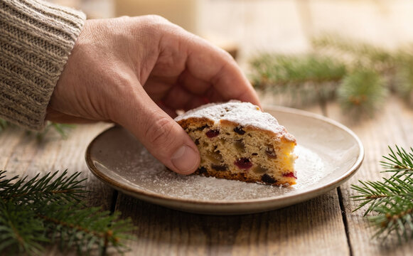 Person holding a slice of Christmas stollen cake with powdered sugar on a plate