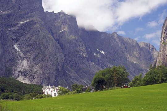 White house on a green field in front of impressive mountain formations and cloudy sky, Tom Cruise filming location, Raumadalen, Trollvegen, Andalsnes, Norway