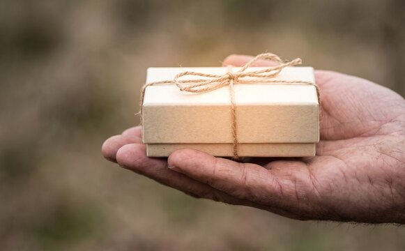 Man holding a small craft gift box with string bow representing surprise and gratitude