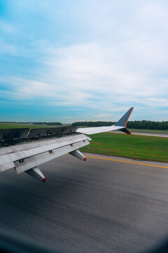 Airplane wing and extended flaps are seen while taxiing beside a green