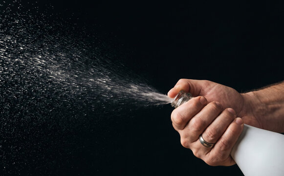 Man hands opening champagne bottle spraying celebration concept with liquid splash on black background